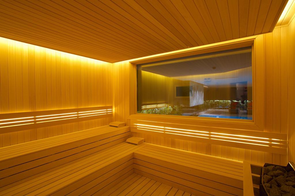 Dosso Dossi Hotels & Spa Downtown Istanbul Luaran gambar The photo depicts a sauna interior characterized by wooden paneling and warm, ambient lighting. The walls and seating are made of light-colored wood, creating a cozy atmosphere. There is a large window that offers a view into another room, possibly f