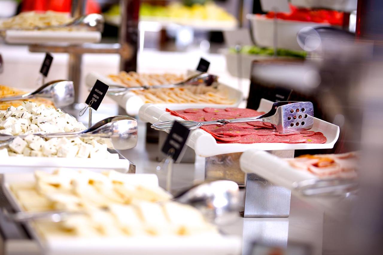 Dosso Dossi Hotels & Spa Downtown Istanbul Luaran gambar The image displays a buffet setting with various food items arranged on tables. There are multiple white serving trays filled with different types of food, including sliced meats, spreads, and possibly salads or other accompaniments. Each tray has a 