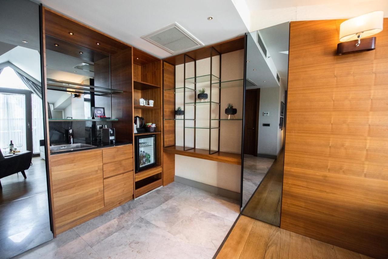 Dosso Dossi Hotels & Spa Downtown Istanbul Luaran gambar The photo shows a modern interior space that features a blend of wood and glass elements. On the left side, there is a kitchenette area with wooden cabinetry and a small refrigerator, while the right side showcases a glass display unit with shelves f