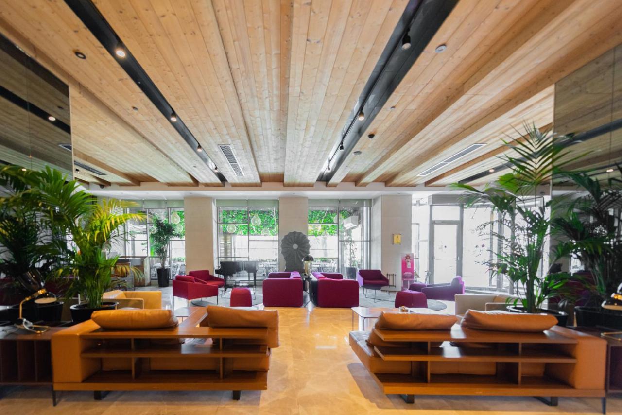 Dosso Dossi Hotels & Spa Downtown Istanbul Luaran gambar The photo shows a modern and spacious lobby area. There are wooden beams on the ceiling, giving the space a warm and inviting atmosphere. The flooring appears to be light-colored stone or tile. 

In the center of the room, there are several seating a