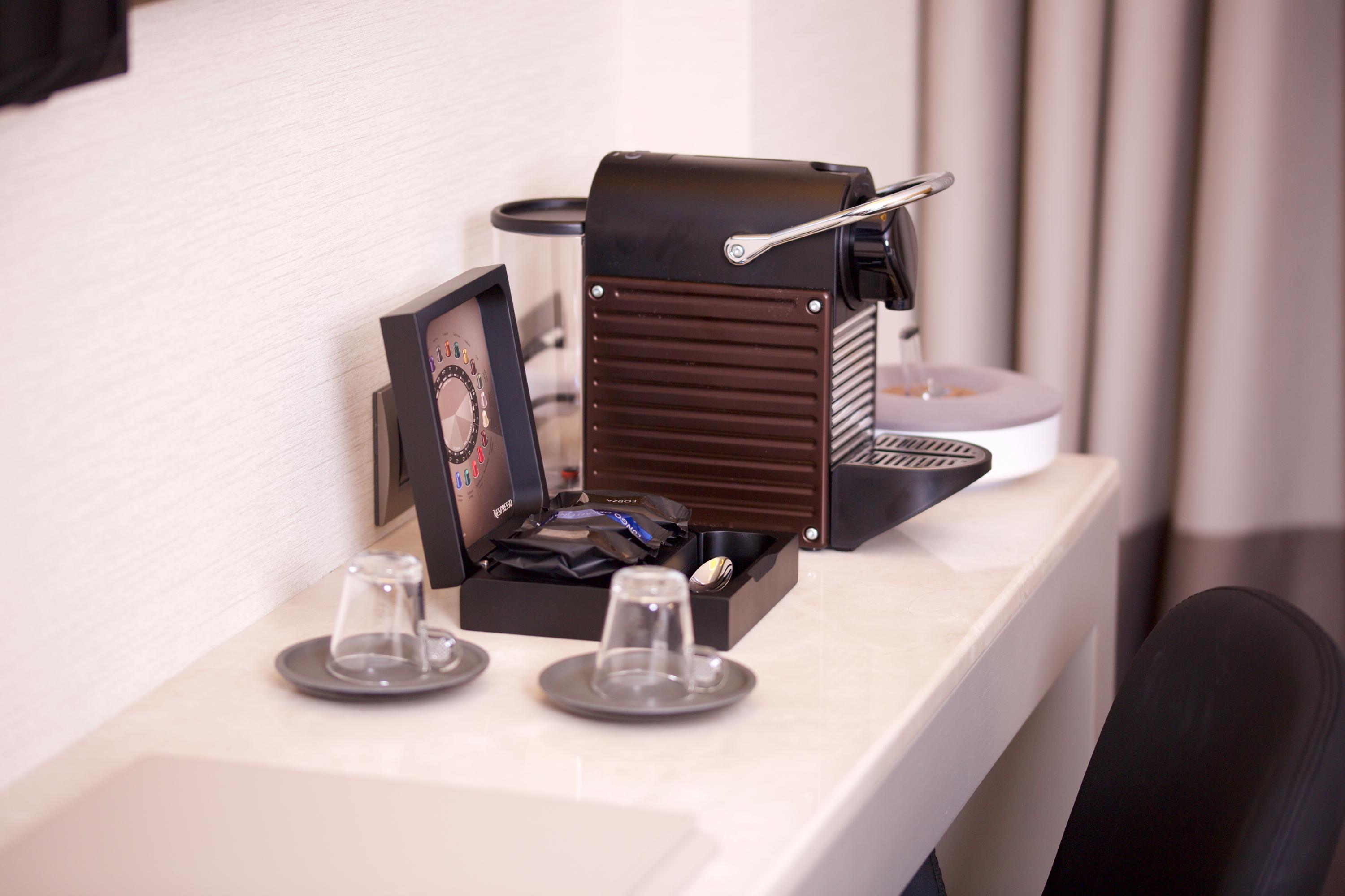 Dosso Dossi Hotels & Spa Downtown Istanbul Luaran gambar The photo shows a coffee machine placed on a light-colored countertop. The machine appears to be a Nespresso-style espresso maker, featuring a sleek, modern design in black. Next to the machine, there is a small decorative box containing coffee pods.