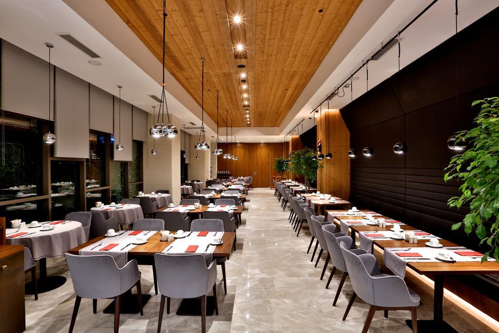 Dosso Dossi Hotels & Spa Downtown Istanbul Luaran gambar The photo depicts a modern restaurant interior. The space features a combination of wooden and polished surfaces, with a prominent wooden ceiling. 

Tables are set with white tablecloths and neatly arranged dishware, indicating a refined dining exper